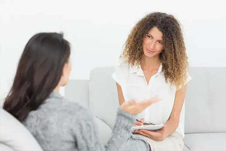 Psychologist discussing assessment with a client in a therapy session.